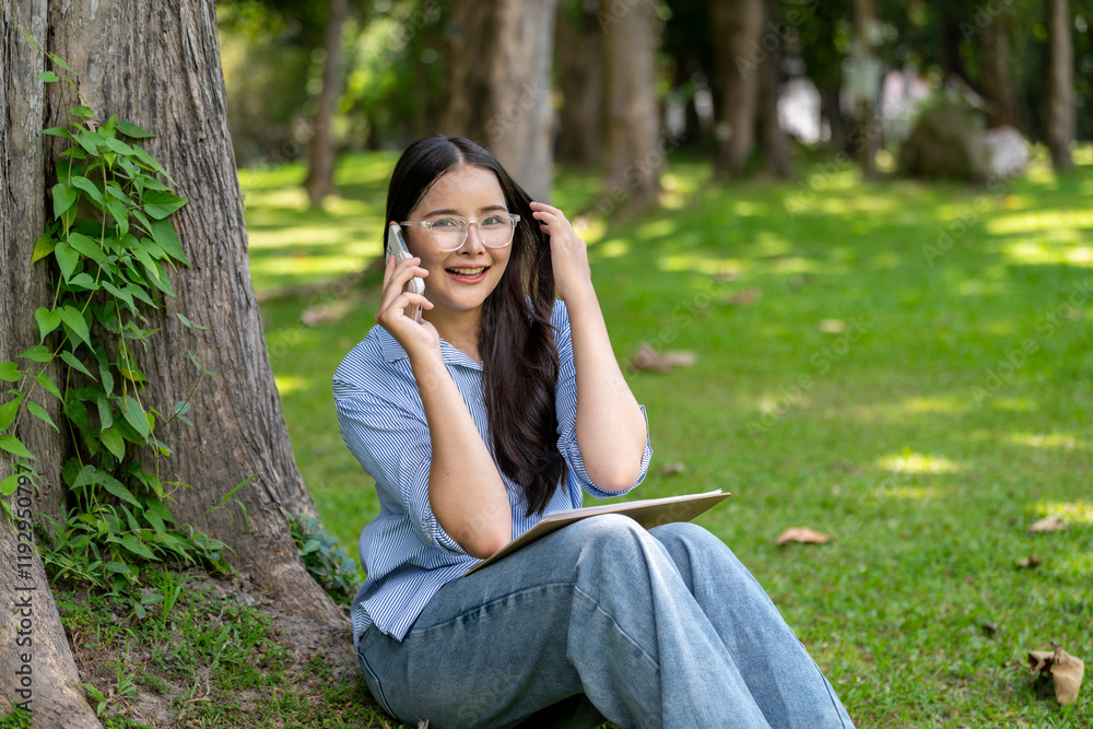 A woman is sitting on the grass and talking on her cell phone A woman is sitting on the grass and talking on her cell phone