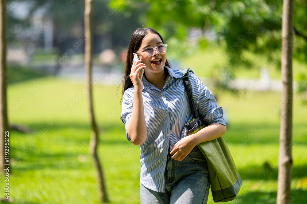 A woman is talking on her cell phone while walking in a park A woman is talking on her cell phone while walking in a park