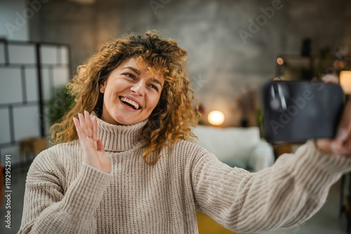 smiling adult woman take a self portrait with mobile phone at home photo