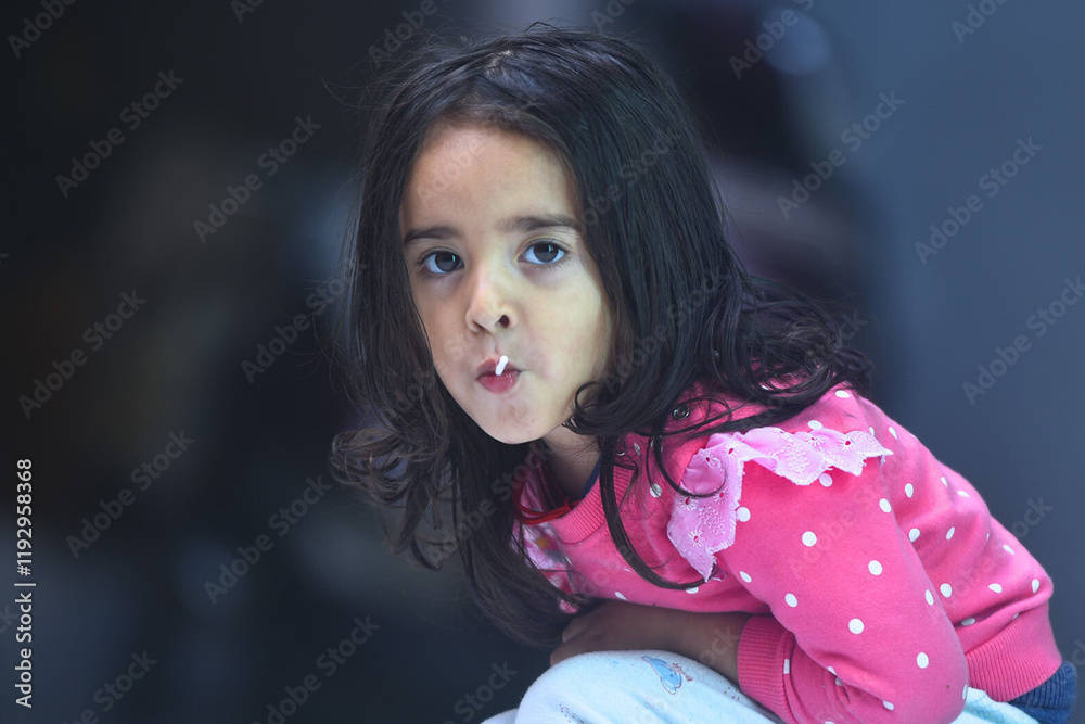 Portrait of a cute and adorable 4 years old Asian Indian baby girl eating lolli pop candy. Portrait of a cute and adorable 4 years old Asian Indian baby girl eating lolli pop candy.