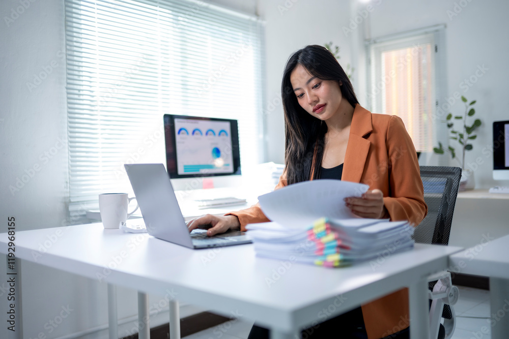 A woman is sitting at a desk with a laptop and a stack of papers A woman is sitting at a desk with a laptop and a stack of papers