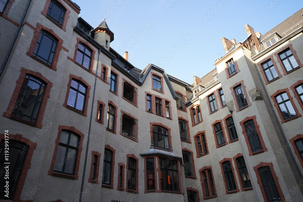 Obraz premium Blick aus dem Hinterhof auf schöne sanierte Fassaden alter Wohnhäuser in Weiß und Naturfarben vor blauem Himmel im Sonnenschein im Stadtteil Mitte in der Hauptstadt Berlin