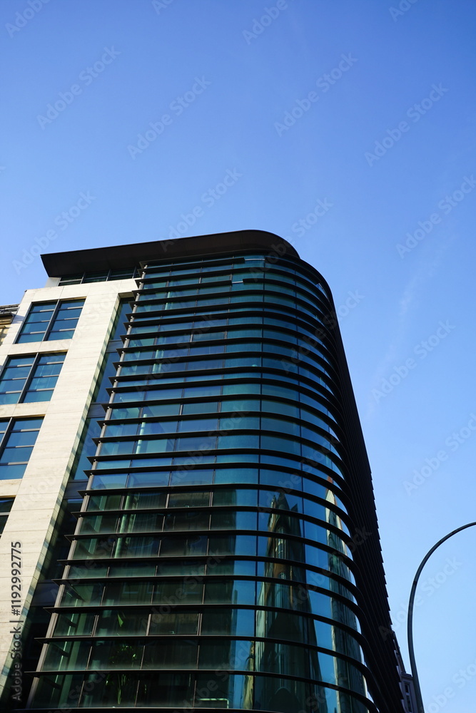 Obraz premium Neubau eines modernen Eckhaus an der Kreuzung Münzstraße und Max-Beer-Straße vor blauem Himmel im Sonnenschein im Stadtteil Mitte in der Hauptstadt Berlin