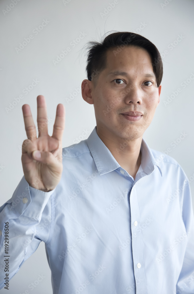 Healthy happy smiling middle aged southeast asian man pointing 3 fingers up, concept of three points, number three, 3rd place on isolated background Healthy happy smiling middle aged southeast asian man pointing 3 fingers up, concept of three points, number three, 3rd place on isolated background