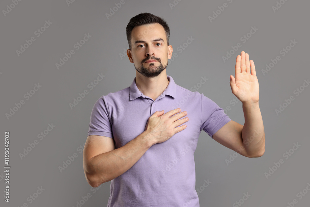 Man making promise with raised hand on grey background. Oath gesture Man making promise with raised hand on grey background. Oath gesture