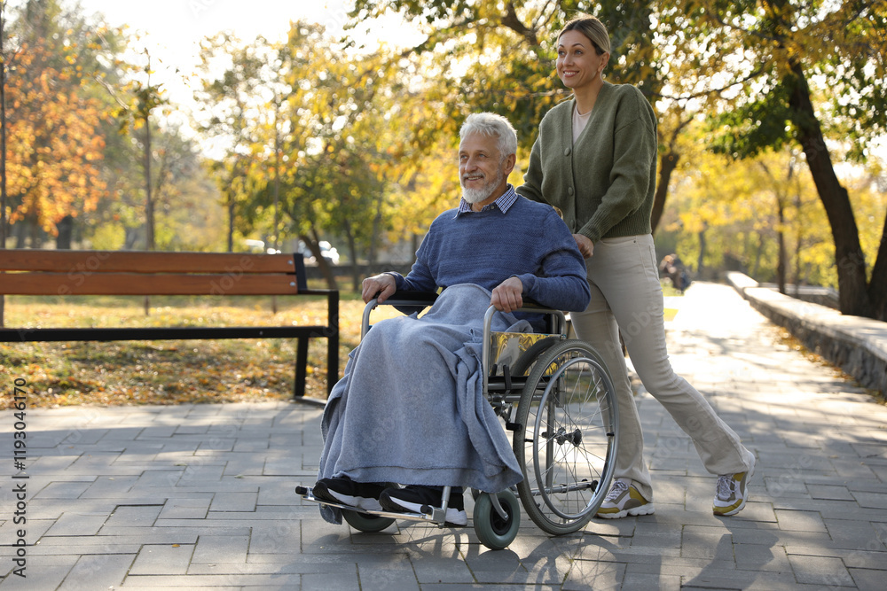 Caregiver assisting senior man on wheelchair in park, space for text. Home health care service Caregiver assisting senior man on wheelchair in park, space for text. Home health care service