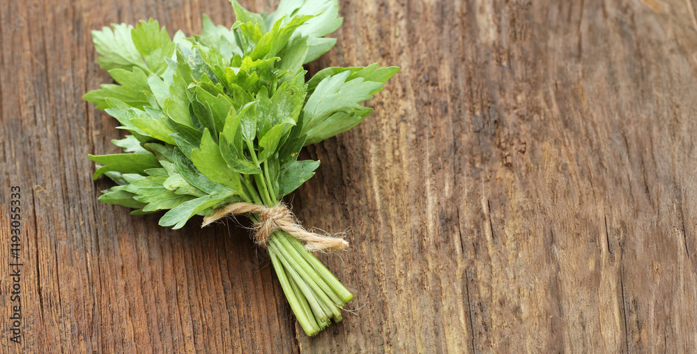 Bunch of lovage herb on wooden background Bunch of lovage herb on wooden background