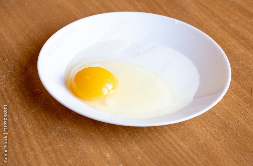 Raw egg in a white plate on the table. Raw egg in a white plate on the table.