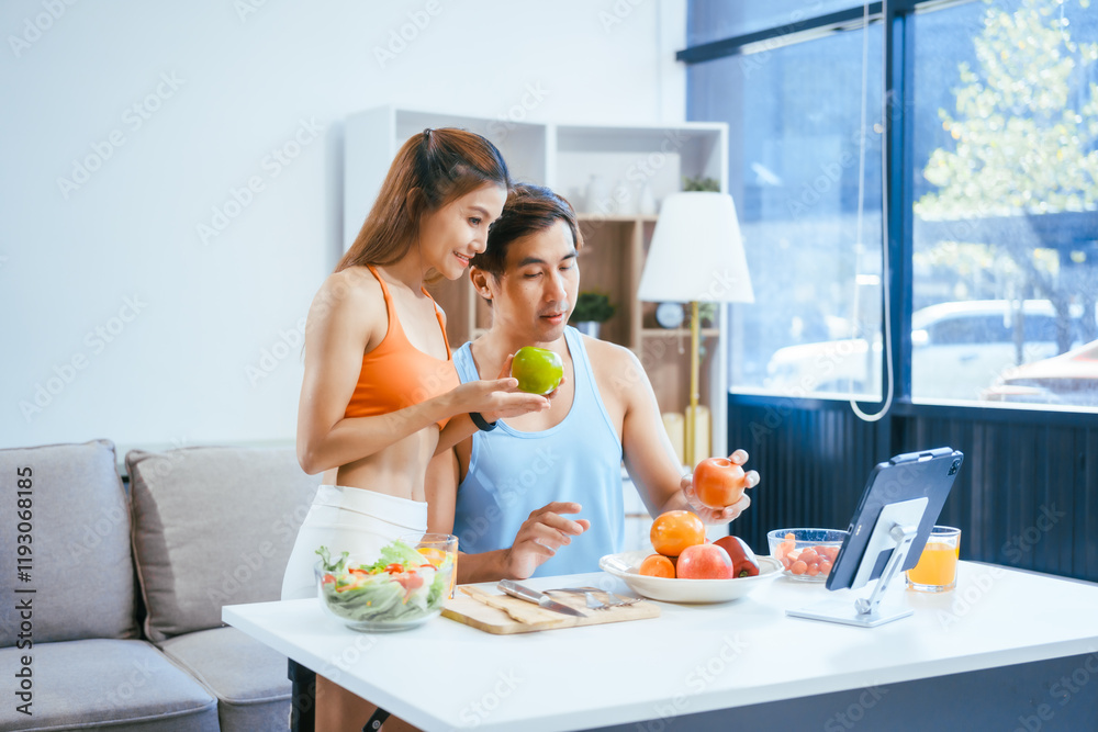 A happy young couple in sportswear sits on the sofa after exercising, enjoying fruits, salad, and orange juice. They focus on weight loss, weight control, and living a healthy lifestyle A happy young couple in sportswear sits on the sofa after exercising, enjoying fruits, salad, and orange juice. They focus on weight loss, weight control, and living a healthy lifestyle