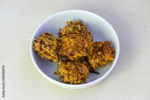 Crispy, crunchy pakora served on a white bowl. These delicious deep-fried fritters are a popular snack or appetizer in Bangladesh, India, and other parts of South Asia. photo