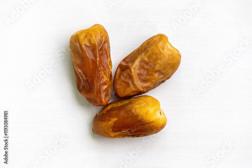 Three dried date palm fruits isolated against a white background. Top view. photo