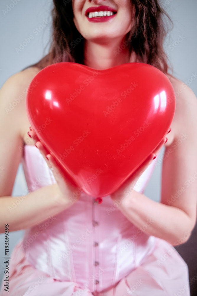 Portrait of a beautiful cheerful kind young woman holding a big red heart, isolated on a blue background, ready for Valentine's Day. Portrait of a beautiful cheerful kind young woman holding a big red heart, isolated on a blue background, ready for Valentine's Day.