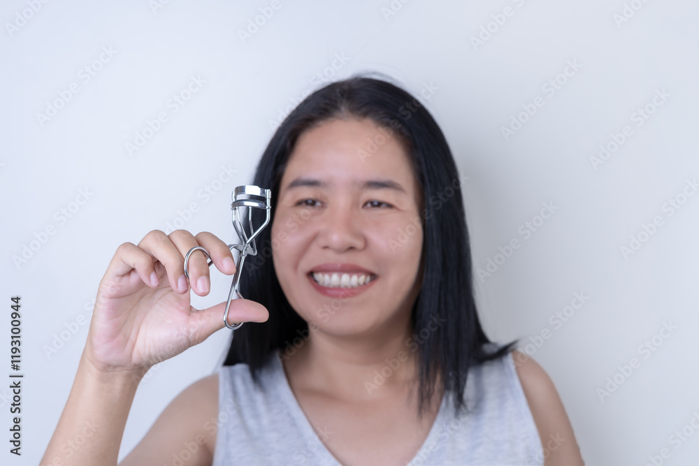 Attractive Asian woman Decorate face with an eyelash curler in hand. Boost your confidence with makeup. Happy Young Woman's Daily Routine Happy beauty concept On a white background. Attractive Asian woman Decorate face with an eyelash curler in hand. Boost your confidence with makeup. Happy Young Woman's Daily Routine Happy beauty concept On a white background.