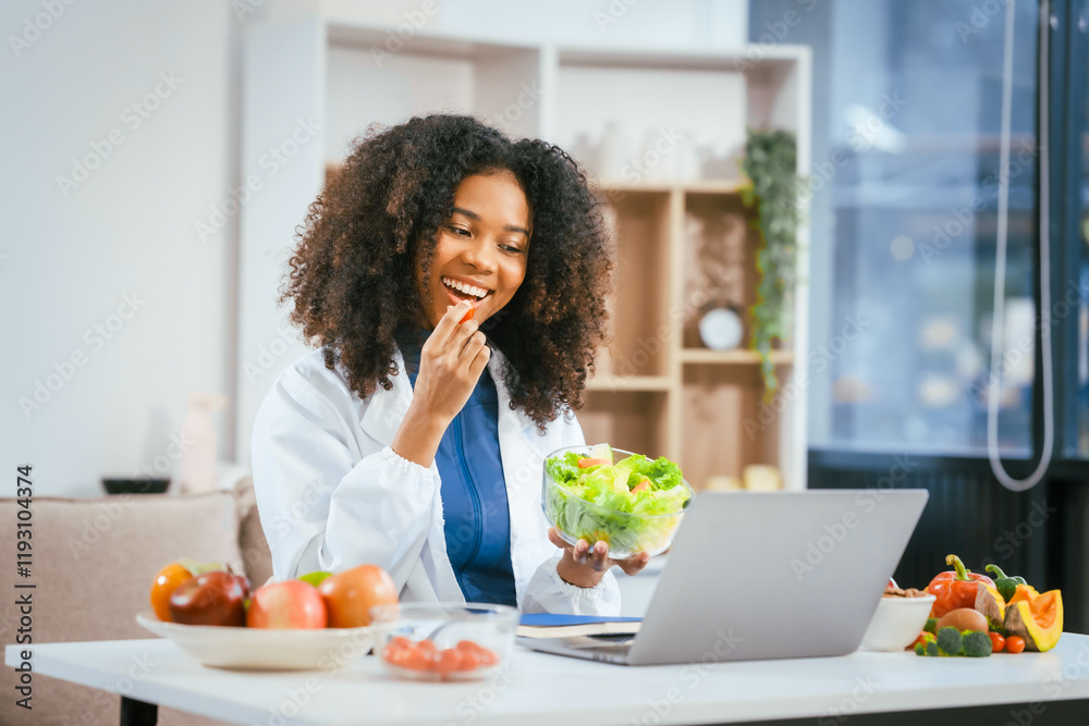 An African American female nutritionist sits at a table, consulting online with patients. She talks about the benefits of eating fruits and vegetables, emphasizing healthy eating and the importance An African American female nutritionist sits at a table, consulting online with patients. She talks about the benefits of eating fruits and vegetables, emphasizing healthy eating and the importance