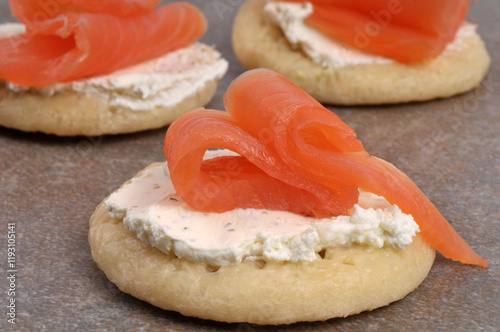 Amuse-bouches faits maison avec du saumon fumé et de la crème sur des blinis isolés sur fond gris photo