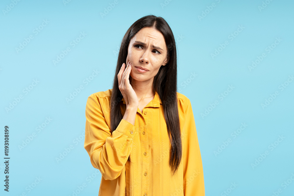 Middle aged Hispanic woman suffering from toothache touching cheek on blue background Middle aged Hispanic woman suffering from toothache touching cheek on blue background