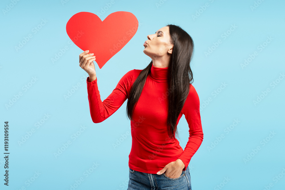 Beautiful woman kissing a red heart on blue background Beautiful woman kissing a red heart on blue background