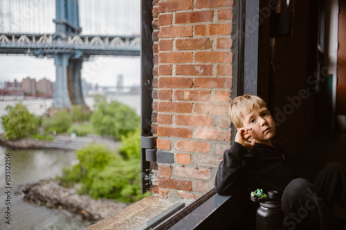 Obraz na płótnie Sad Boy close to window with Manhattan Bridge in the background, in New York City - USA w salonie