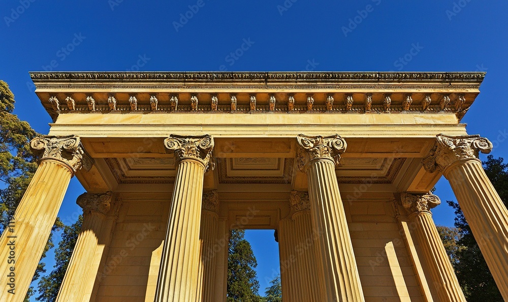 Fototapeta premium Classical temple facade with columns against blue sky, ideal for history or architecture projects