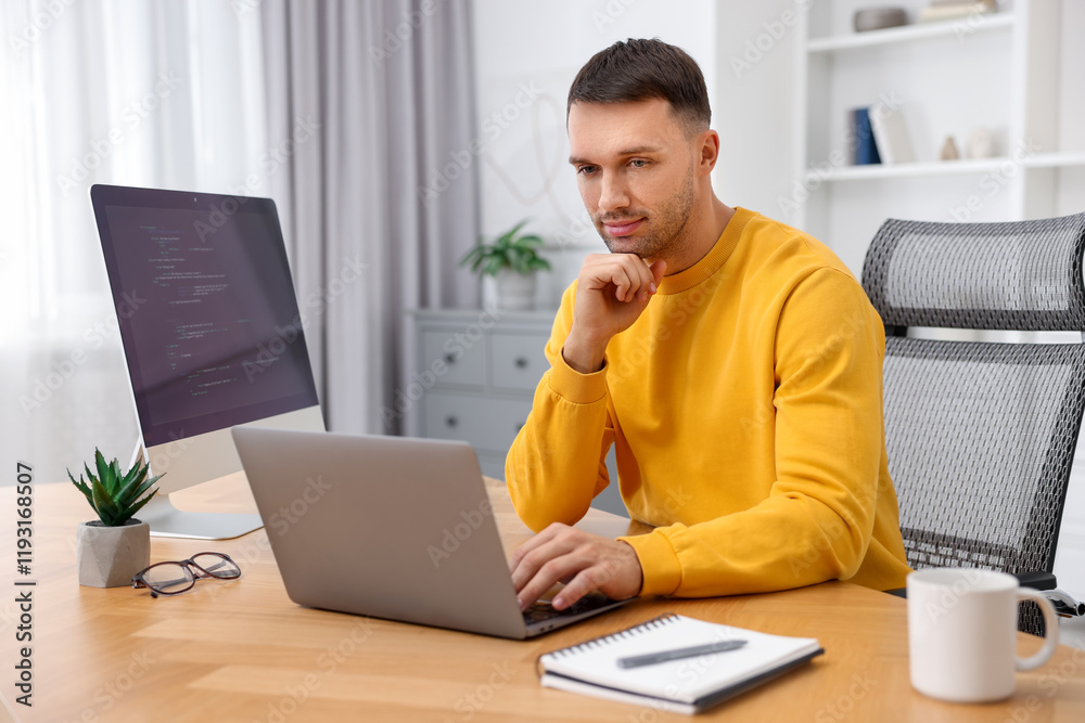 Programmer working on laptop at wooden desk indoors Programmer working on laptop at wooden desk indoors