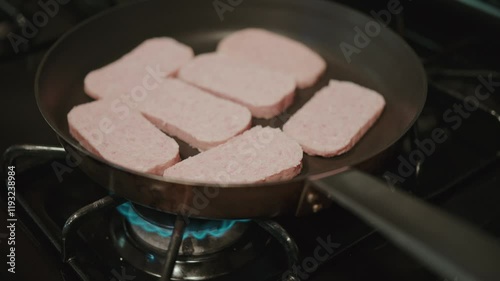 Closeup footage of cooking processed canned ham meat in a frying pan on a lit stove photo