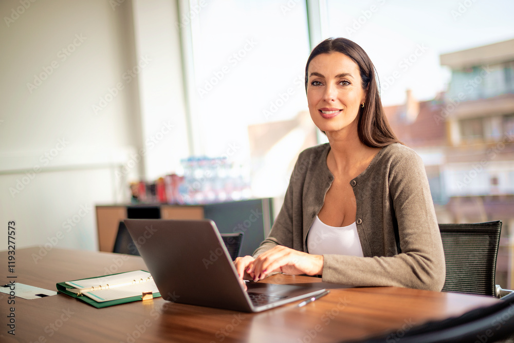 Attractive businesswoman using her laptop at office desk