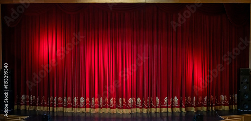 Theatre red velvet curtain with elegant gold pattern and fringe at the bottom edge.