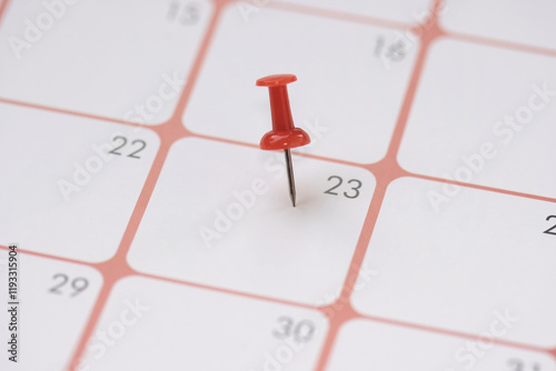 Calendar entry: Number 23 pinned with a red push pin or thumbtack, symbolizing the “Save the Date” concept. photo