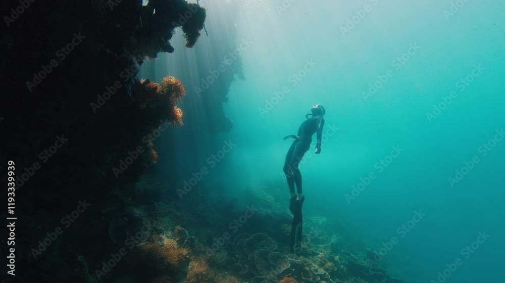 Freediver swims underwater near the vivid coral reef in Raja Ampat region in Indonesia