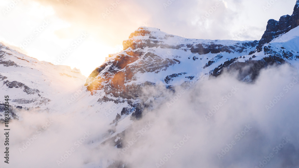 Fototapeta premium Scenery aerial view, drone flying through clouds to mountain snowy pines with frost in winter, bird’s eye view of beautiful nature landscape under breathtaking sky