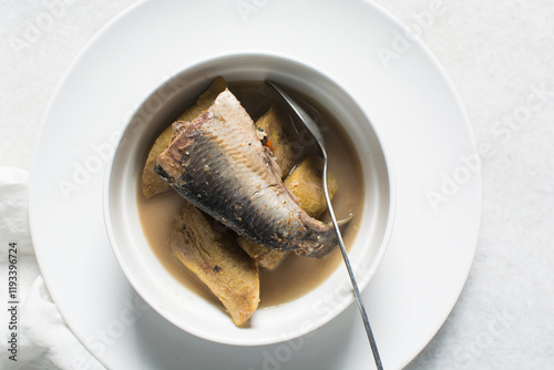 Overhead view of Nigerian pepper soup with fish and plantain in a white soup plate, top view of fish pepper soup in a white plate photo