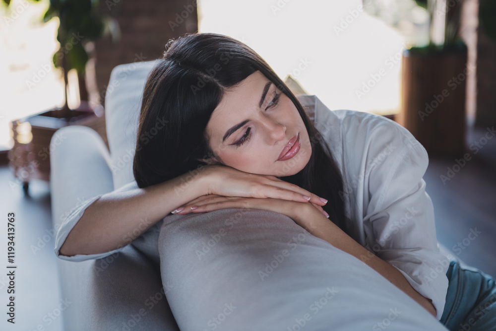 Young woman resting indoors on a couch, enjoying quiet daylight in a casual setting Young woman resting indoors on a couch, enjoying quiet daylight in a casual setting