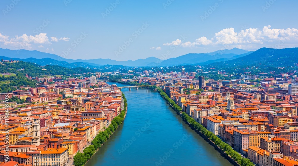 Fototapeta premium Panoramic view of a city with a river flowing through it, surrounded by mountains under a clear sky.