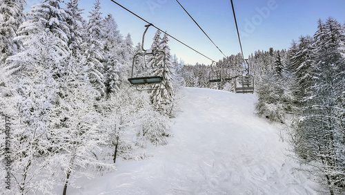 empty chairlift in beautiful snowy mountains in frozen forest in french alpin...