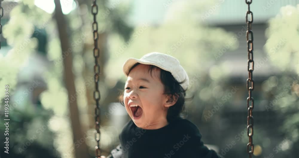 Cheerful boy swings joyfully in 4K slow motion at outdoor playground. Wears white cap, black long-sleeved shirt, wavy medium-length hair, bright smile, playful scene. Cheerful boy swings joyfully in 4K slow motion at outdoor playground. Wears white cap, black long-sleeved shirt, wavy medium-length hair, bright smile, playful scene.