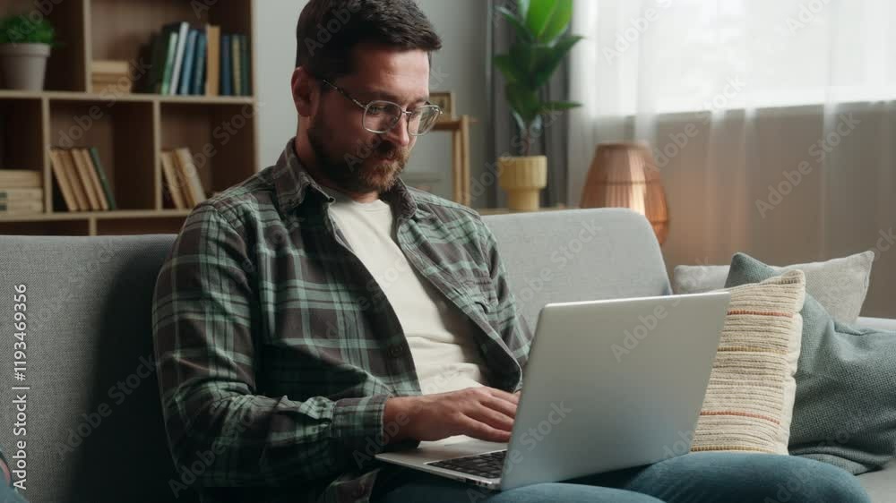 Smiling satisfied Caucasian adult man male guy shopping laptop at home couch playing game online buying internet purchase web browsing working distant computer website showing thumb up like recommend