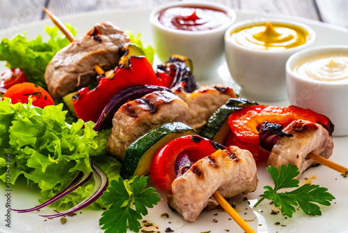 Meat skewers - grilled meat with vegetables on wooden background	