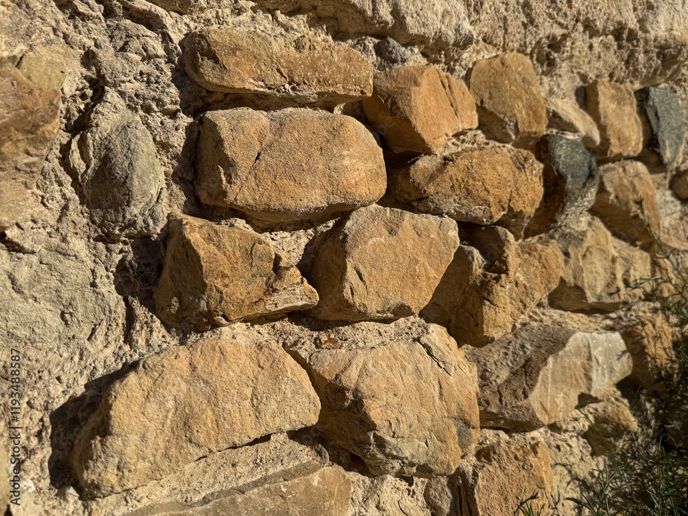 Closeup of rustic stone wall with sunlit textures Closeup of rustic stone wall with sunlit textures