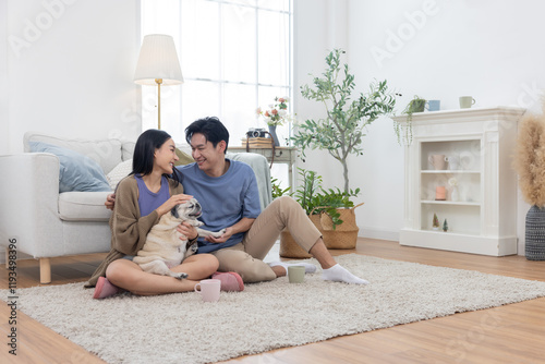 Asian couple spends quality time with their pug dog in their living room