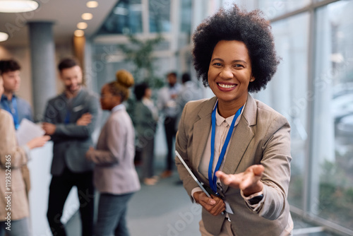 Принти на полотні Happy black presenter welcoming business seminar attendees at convention center and looking at camera