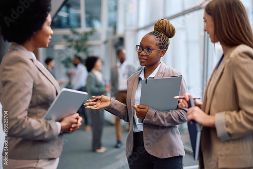 Multiracial group of businesswomen communicating while attending seminar in conference hall.