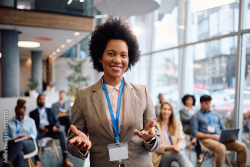 Black female business leader giving speech on seminar and looking at camera.