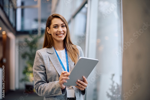 Happy businesswoman working on digital tablet in office and looking at camera.