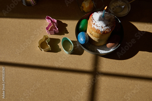 Easter cake with colored eggs and cookie cutters illuminated by sunlight photo