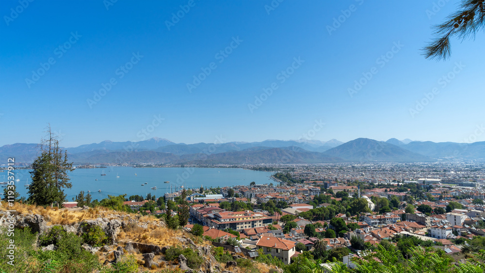 Naklejka premium View of Fethiye city, marina and Mediterranean Sea, Turkey. Walking around resort town at foot of the mountains in southwestern Turkiye