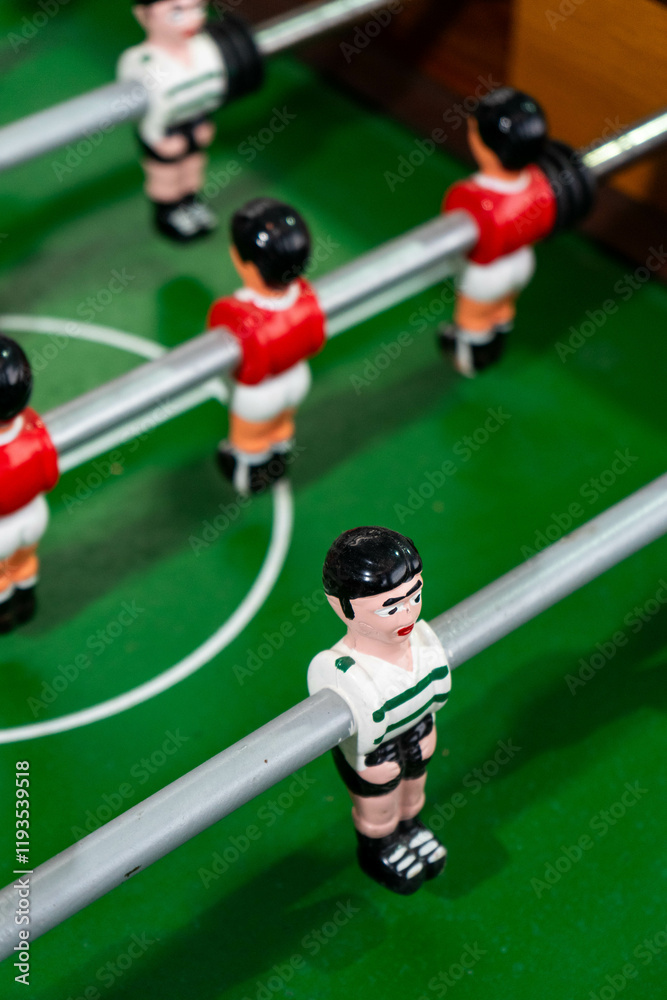 Fototapeta premium Foosball table with players representing Sport Lisboa e Benfica and Sporting Clube de Portugal, highlighting a friendly football rivalry in a playful setting.