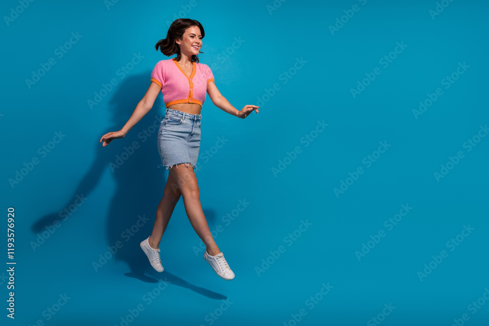Smiling young woman jumping against blue background in casual summer outfit Smiling young woman jumping against blue background in casual summer outfit