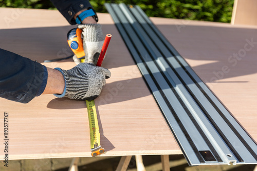 Male using ruler to measure board before cutting using an electric saw