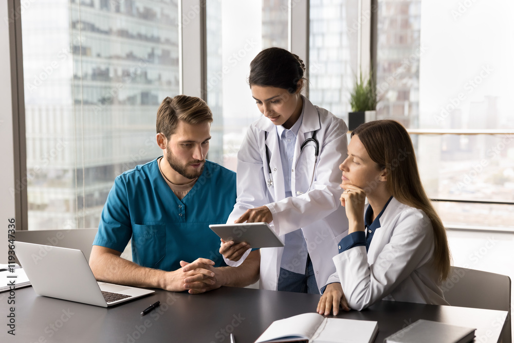 Three multinational doctors working using digital tablet, talking, reviewing patient electronic health records, analyze recent test results, medical history, medication lists, and previous diagnoses Three multinational doctors working using digital tablet, talking, reviewing patient electronic health records, analyze recent test results, medical history, medication lists, and previous diagnoses