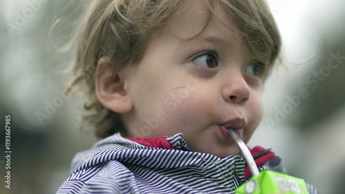 Child drinking juice with straw, little boyd drink snack photo